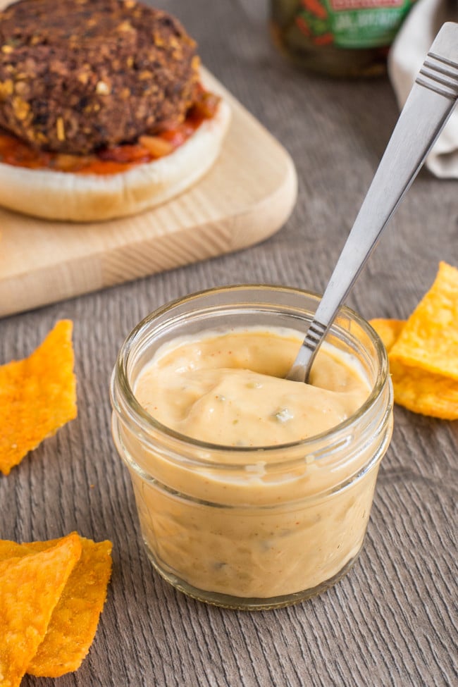 Vegetarian nacho burgers with homemade nacho cheese sauce - these are so good! A simple black bean burger made with crushed tortilla chips and jalapenos, and topped with salsa and avocado. Yum!