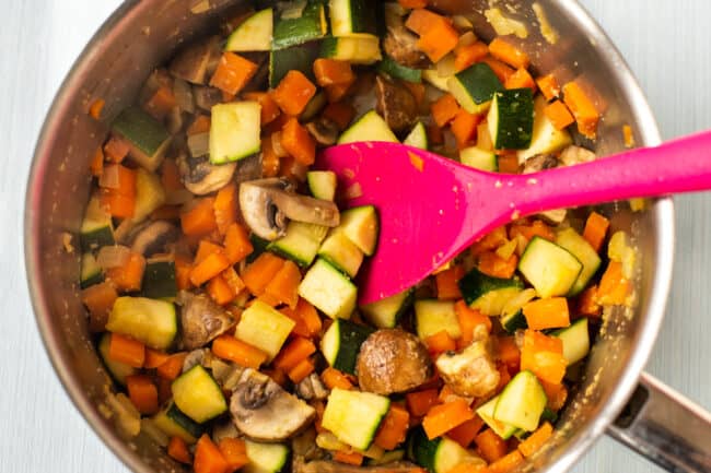 Diced vegetables being cooked in a saucepan.