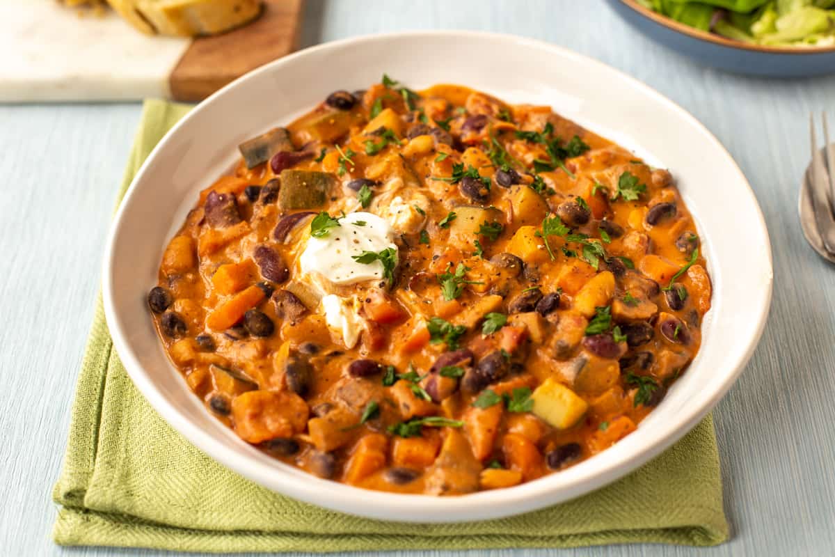 A bowlful of creamy three bean stew topped with parsley and a dollop of sour cream.