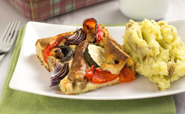 Vegetable toad in the hole - vegetarian sausages and roasted veggies, all cooked in a Yorkshire pudding batter. A classic British recipe!
