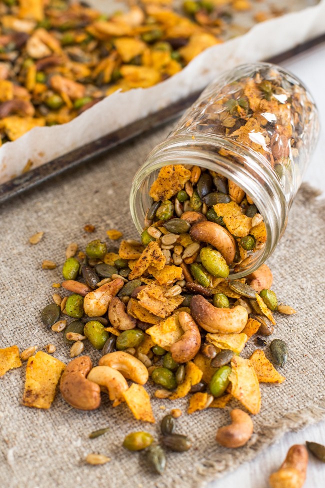 Homemade savory trail mix spilling out of a jar.