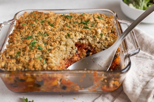 A baking dish containing a rich tomatoey halloumi casserole, topped with garlicky breadcrumbs.
