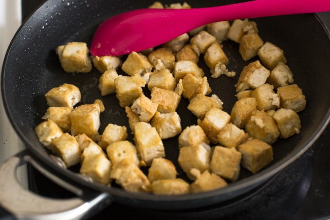 Crispy tofu coated in cornstarch, cooking in a frying pan