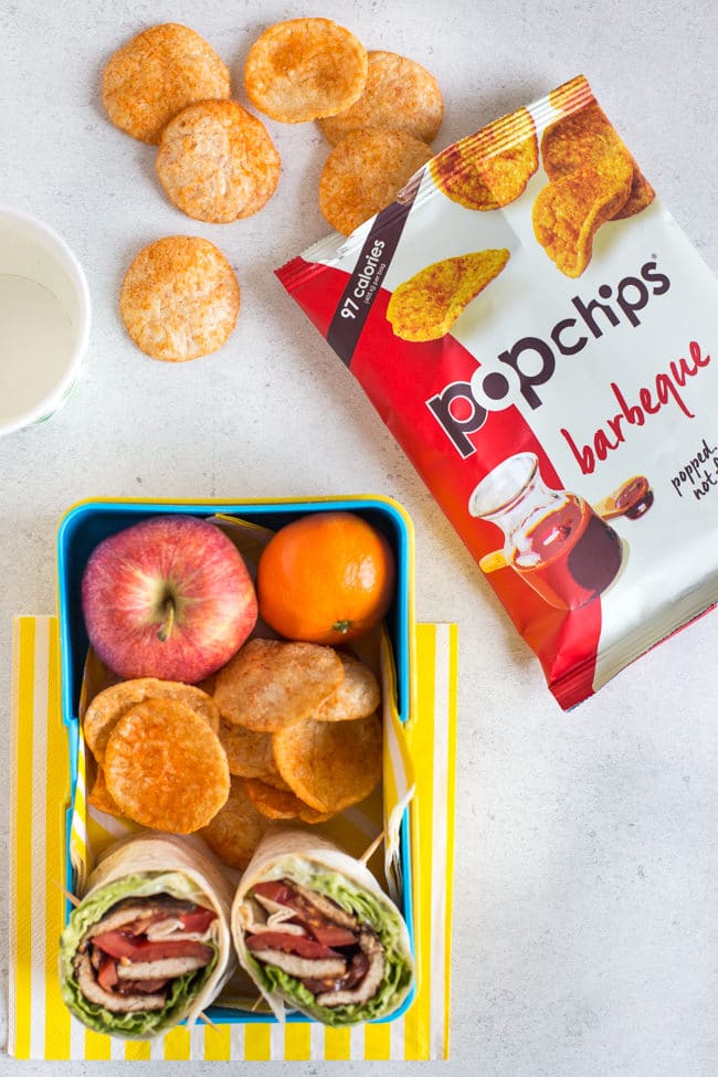 Barbeque popchips served alongside a lunchbox filled with tofu bacon BLT wraps and fruit