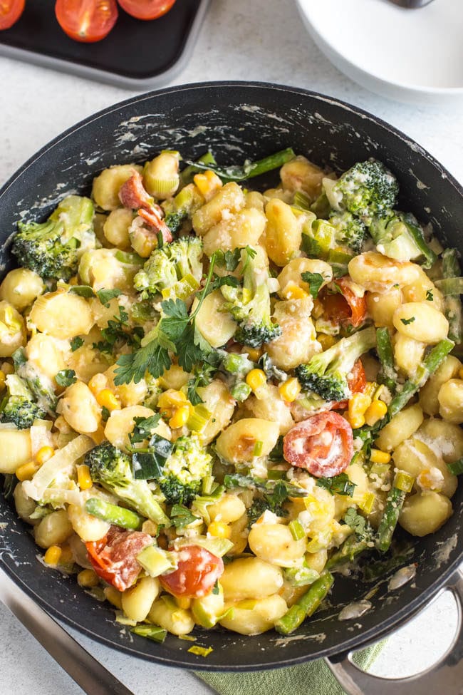 Colourful gnocchi primavera in a frying pan, shot from above, with broccoli, asparagus and tomatoes