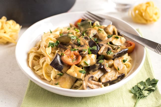Creamy veggie marsala with tagliatelle in a white bowl with a fork
