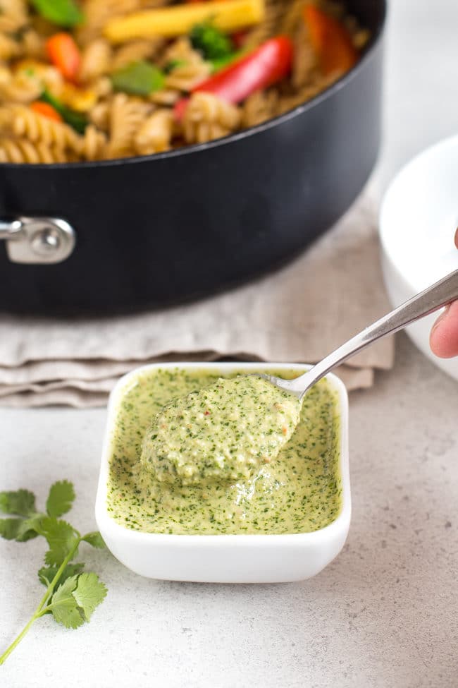 Thai pesto in a small white bowl, being scooped with a spoon