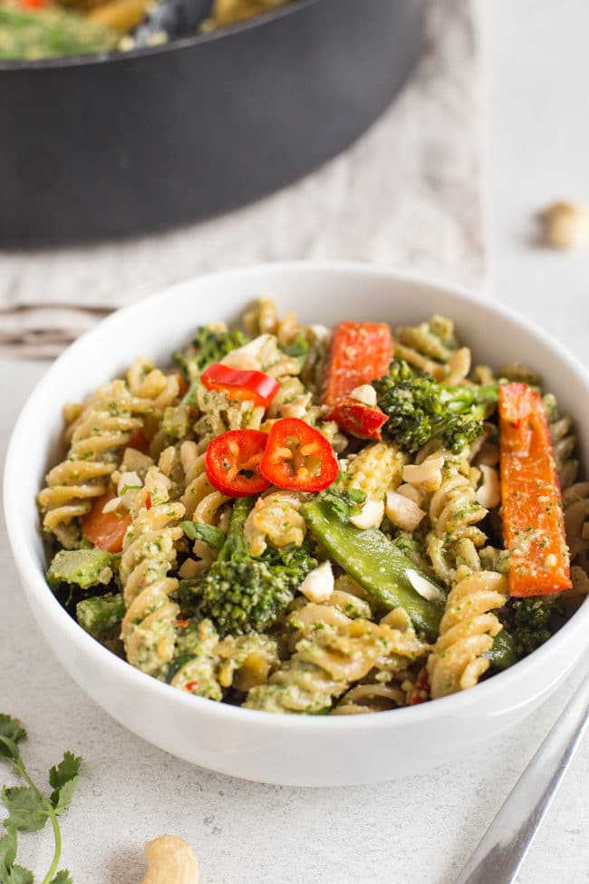Thai pesto pasta with lots of vegetables in a white bowl