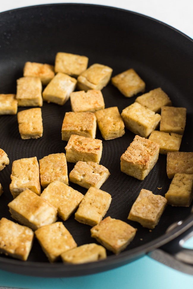 Crispy tofu cubes cooking in a frying pan