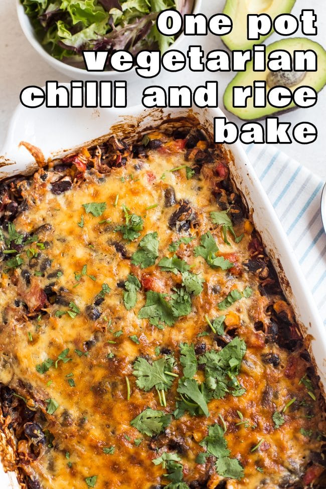 Cheesy vegetarian chilli and rice bake in a white baking tray, shot from above