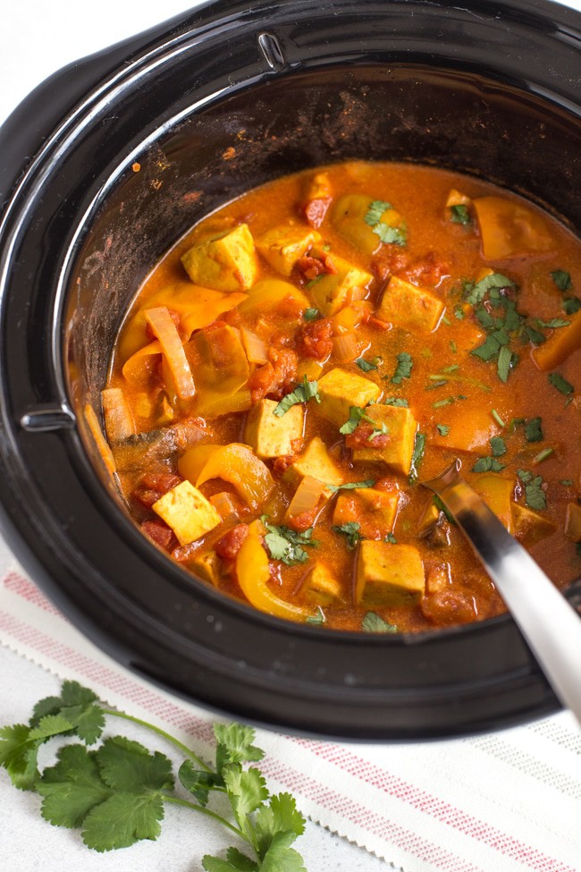 Paneer tikka masala in a slow cooker with a spoon and fresh coriander
