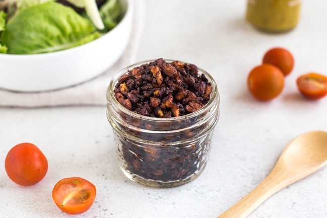 Homemade tofu bacon bits in a glass jar with lettuce and tomatoes
