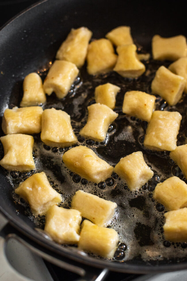 Ricotta gnocchi cooking in a frying pan.