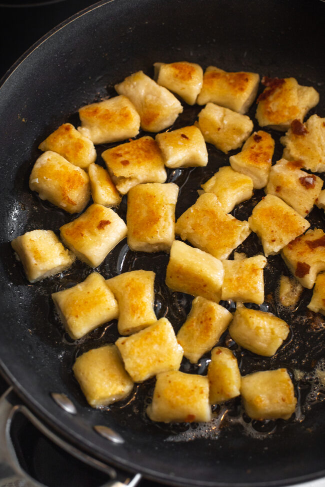 Crispy fried ricotta gnocchi in a frying pan.