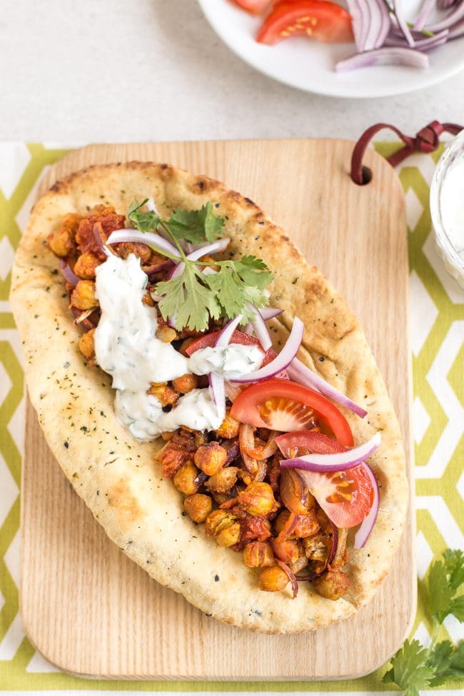 Indian roasted chickpea flatbread shot from above on a wooden board with yogurt sauce