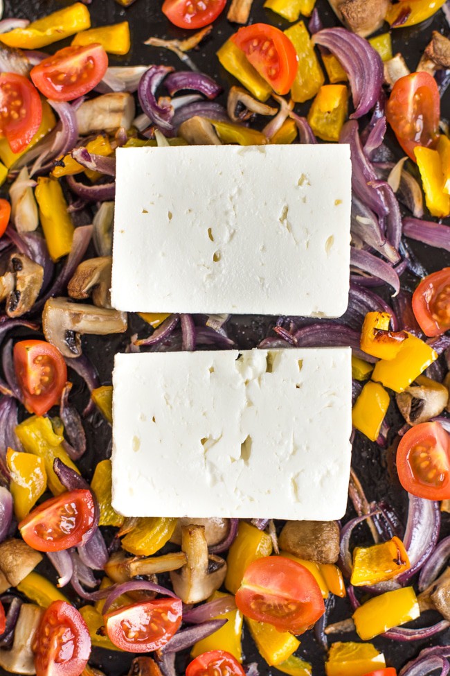 Slices of feta cheese on top of part-roasted Mediterranean vegetables