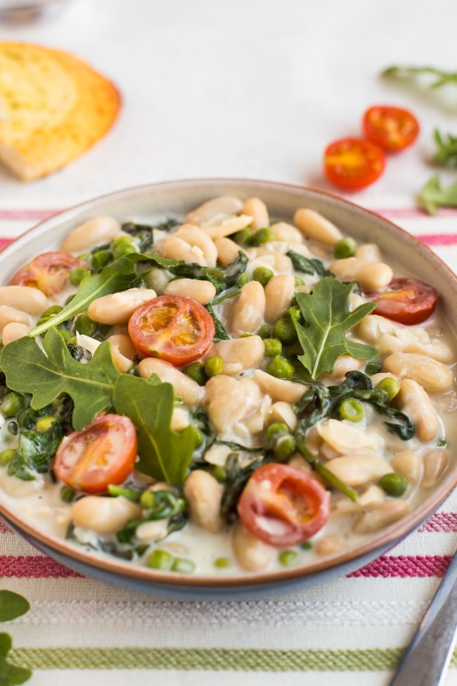 Creamy white beans with tomatoes and rocket in a bowl