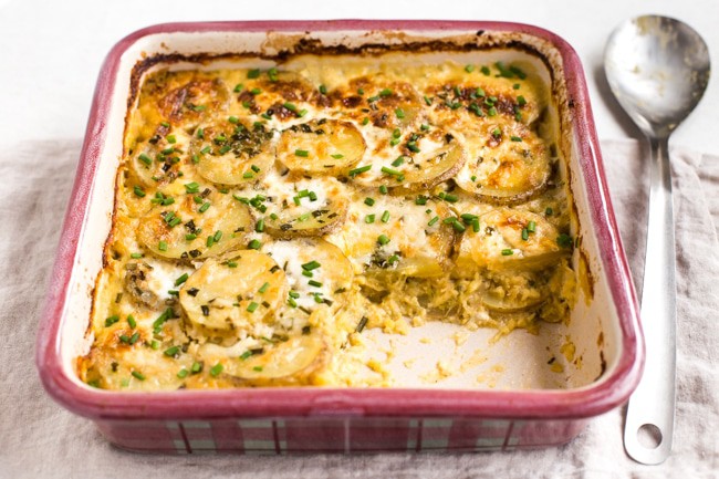 Goat's cheese and potato lentil gratin in a baking dish with a portion removed