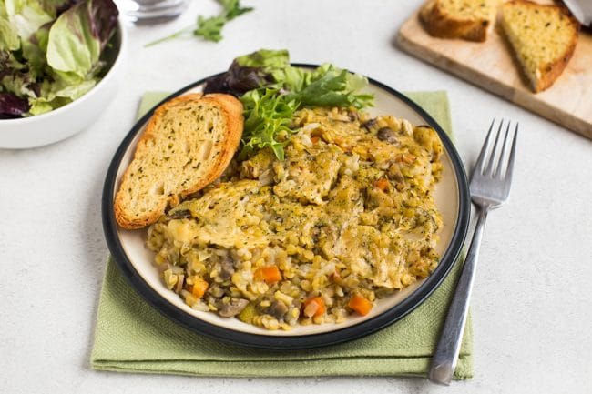 Portion of Instant Pot lentil bake on a plate with garlic bread and salad