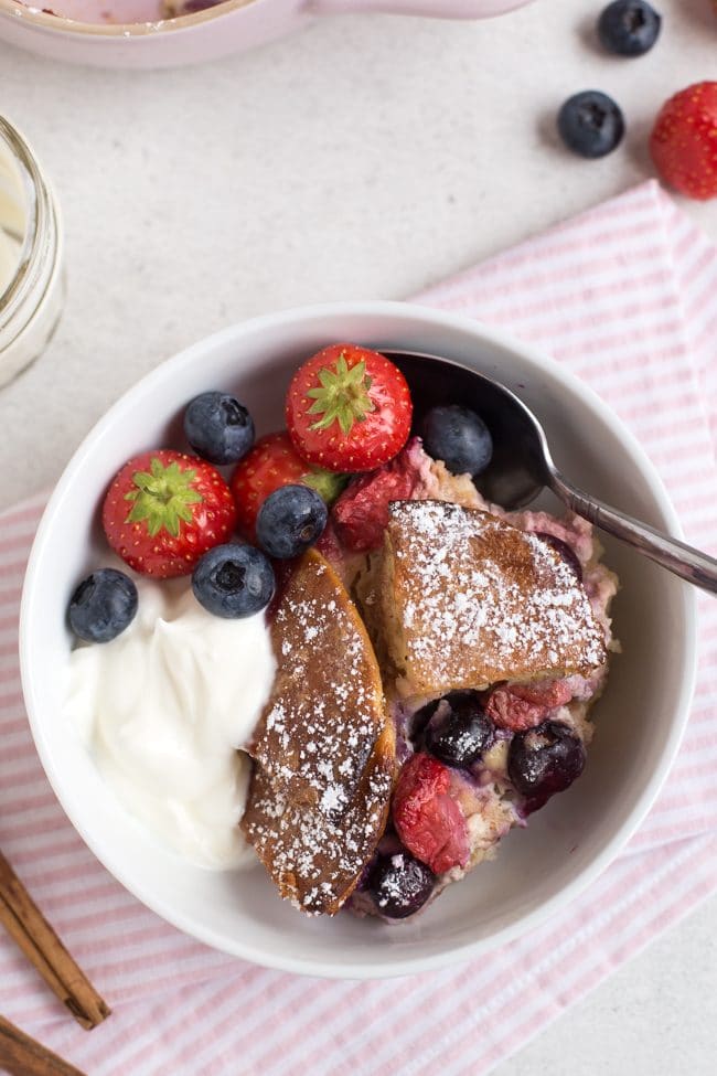 Portion of pancake pudding in a bowl with Greek yogurt and fresh berries