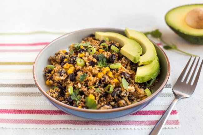 Portion of Tex-Mex cauliflower rice in a bowl with sliced avocado