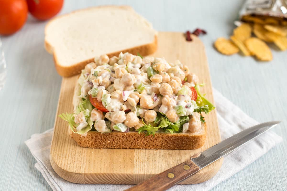 A creamy chickpea salad sandwich with its top removed.