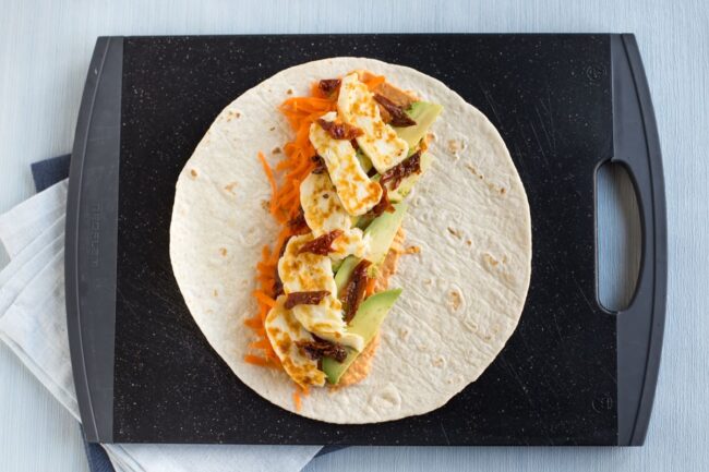 Large flour tortilla topped with halloumi, avocado and sun-dried tomatoes