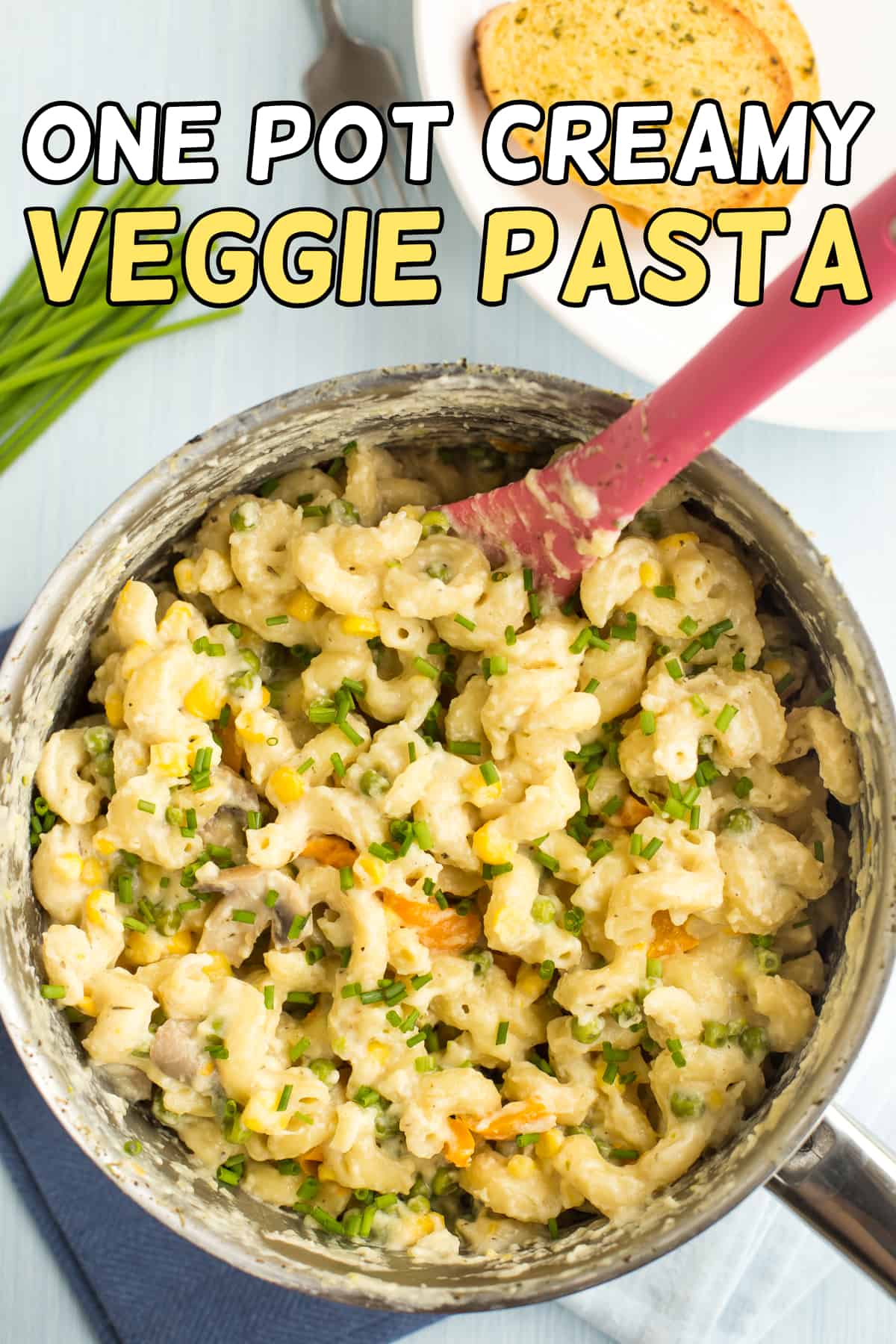 One pot creamy veggie pasta in a saucepan topped with chives.