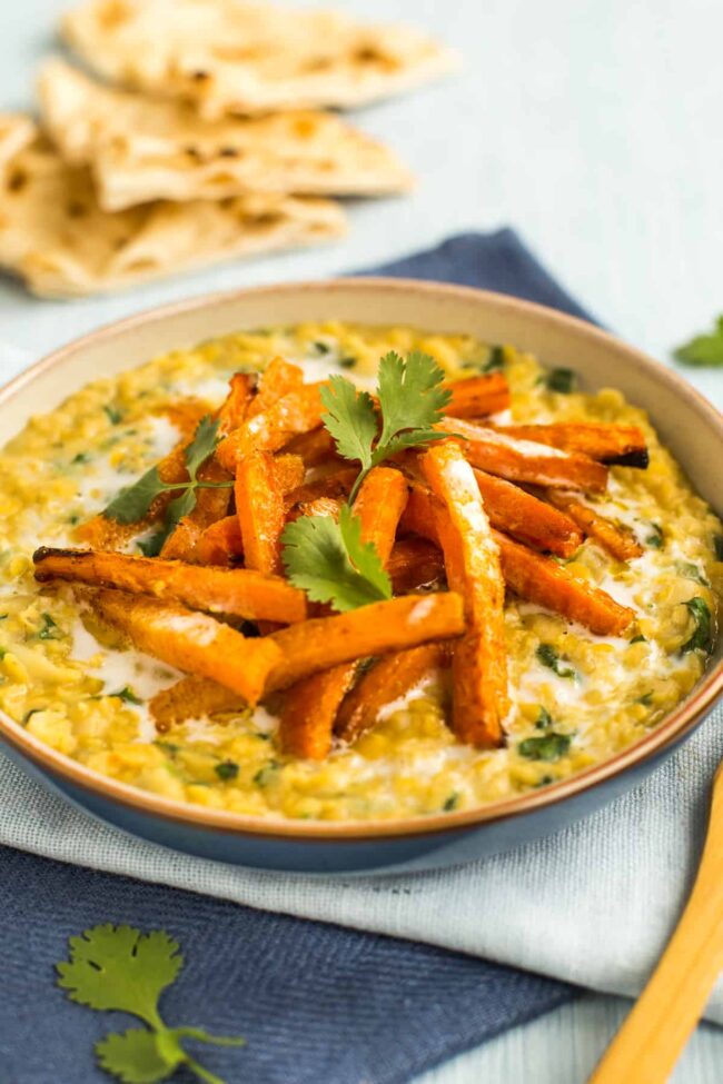 Portion of creamy lentils in a bowl topped with roasted carrots.