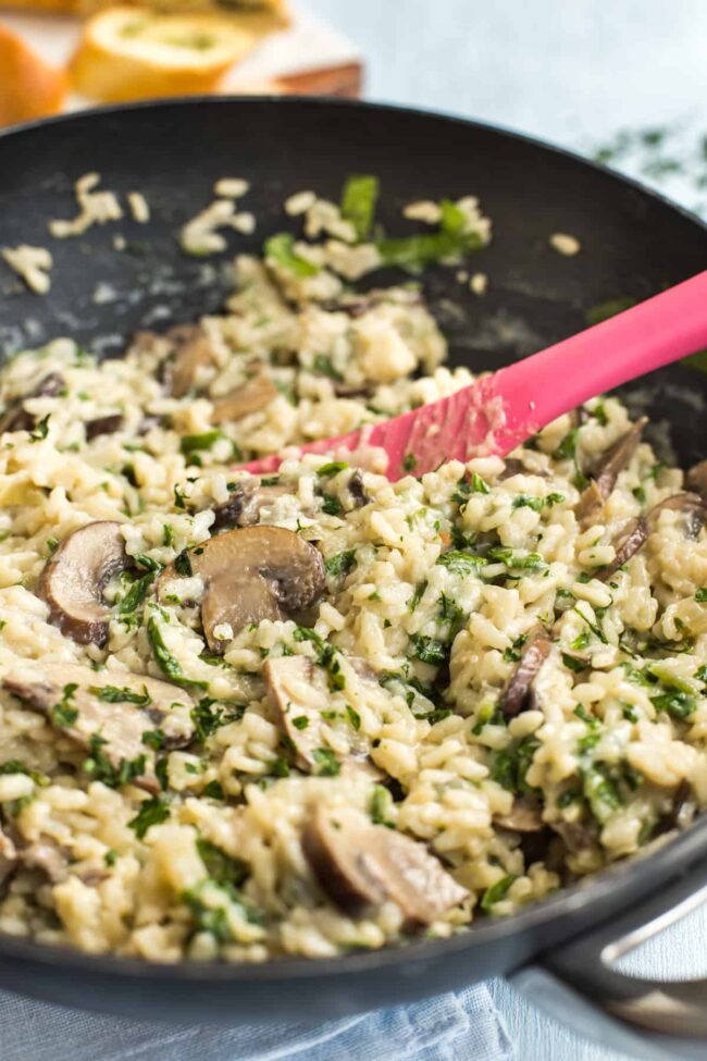 Creamy spinach and mushroom risotto in a wok topped with parsley.