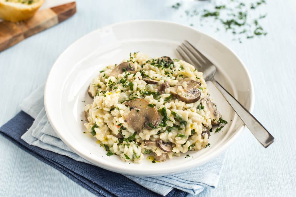 Portion of mushroom risotto in a bowl topped with parsley.