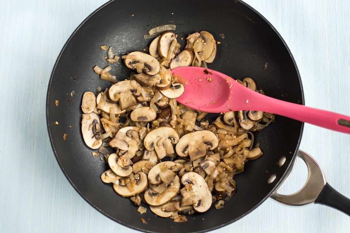 Garlic mushrooms with onion cooking in a wok.