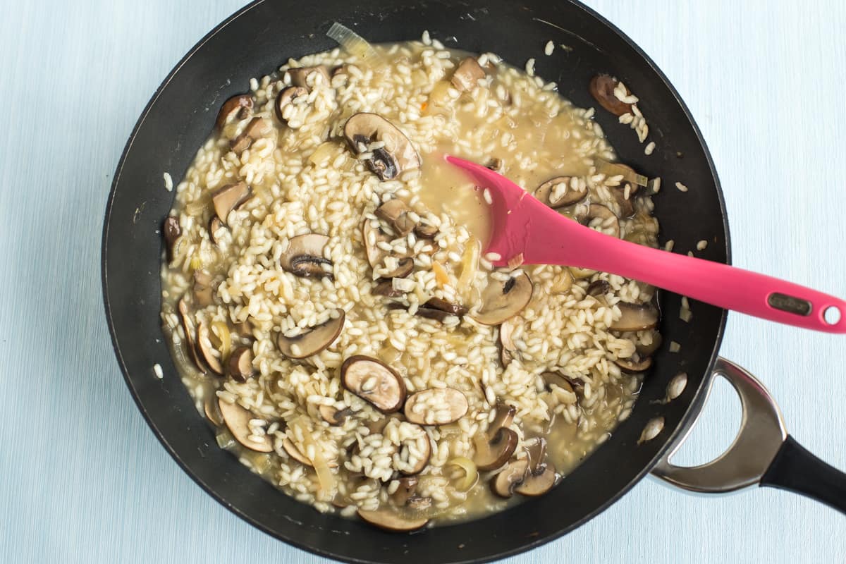 Part-cooked mushroom risotto in a wok.