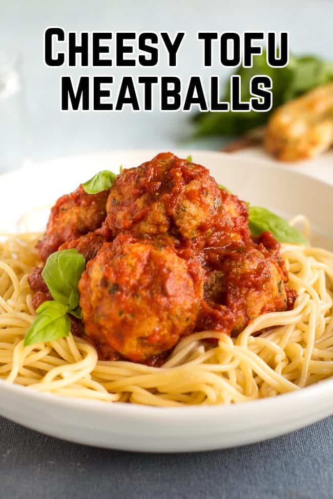 Portion of cheesy tofu meatballs in a bowl with spaghetti and fresh basil