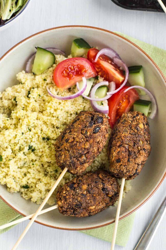 Black bean and lentil vegetarian koftas served with couscous and tomato salad.