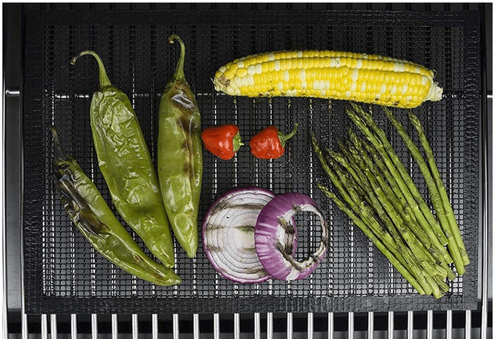 A mesh BBQ grill mat being used to cook various vegetables.