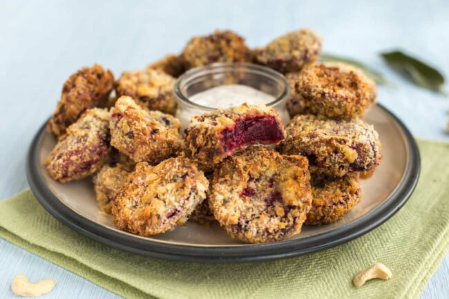 A plateful of beetroot nuggets with a pot of creamy sauce.