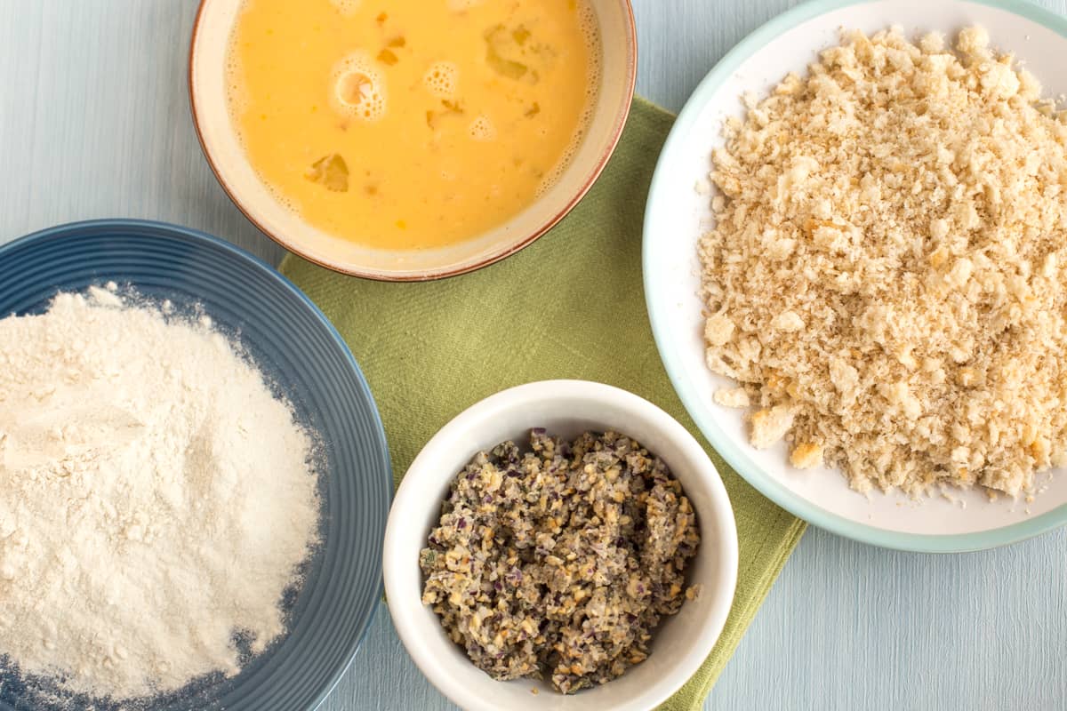 Ingredients for breading - flour, eggs, and breadcrumbs in small dishes.