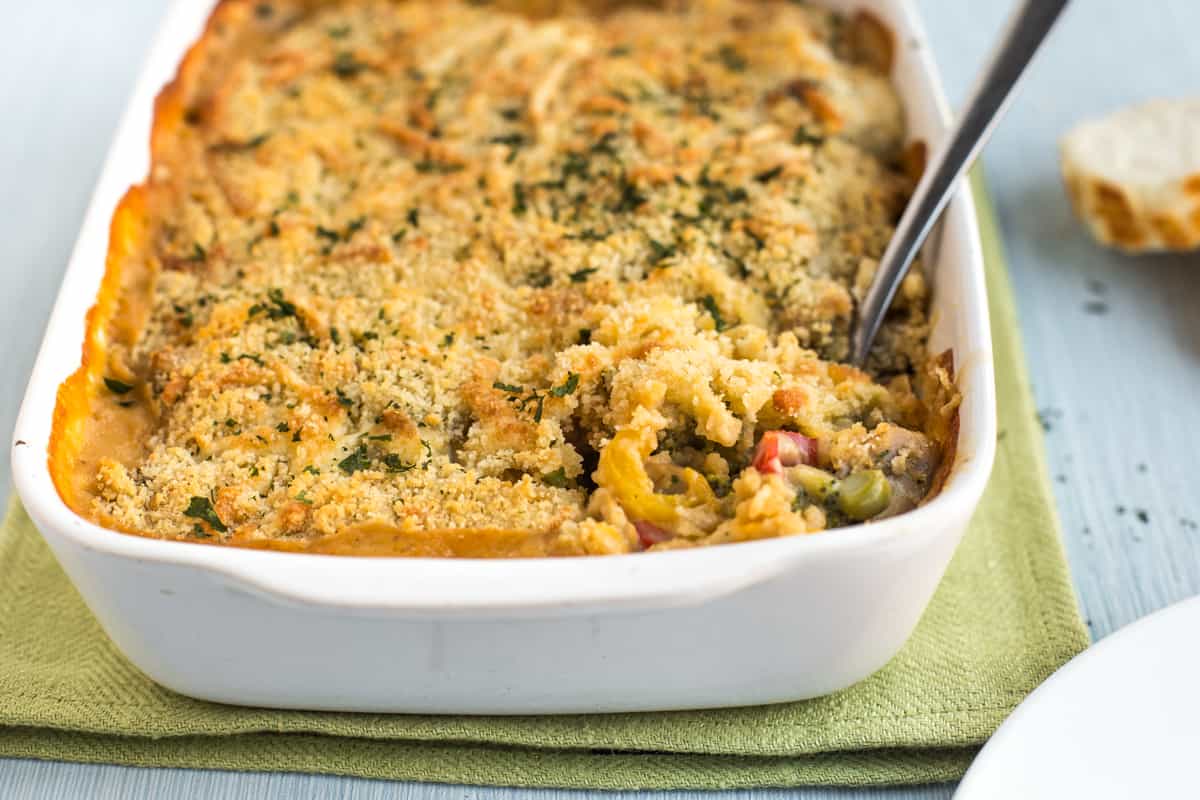 Creamy vegetable bake in a baking dish with a spoon scooping out a portion.