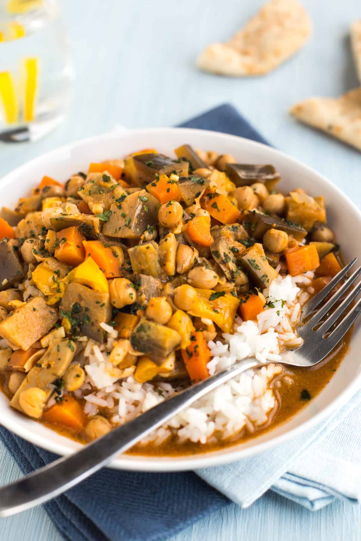 Bowlful of chickpea curry with vegetables and rice.