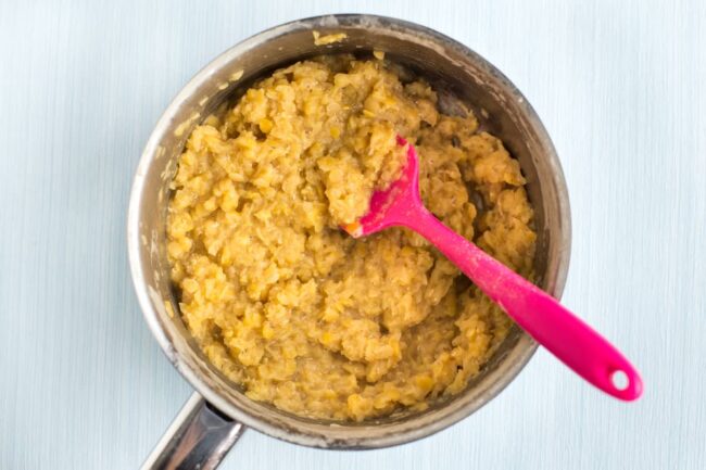 Cooked red lentils in a small pan.