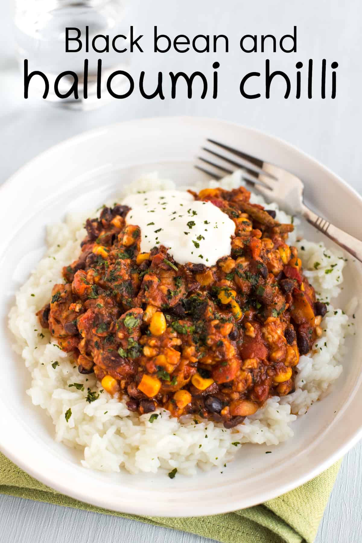 A portion of halloumi chilli in a bowl with rice and sour cream.