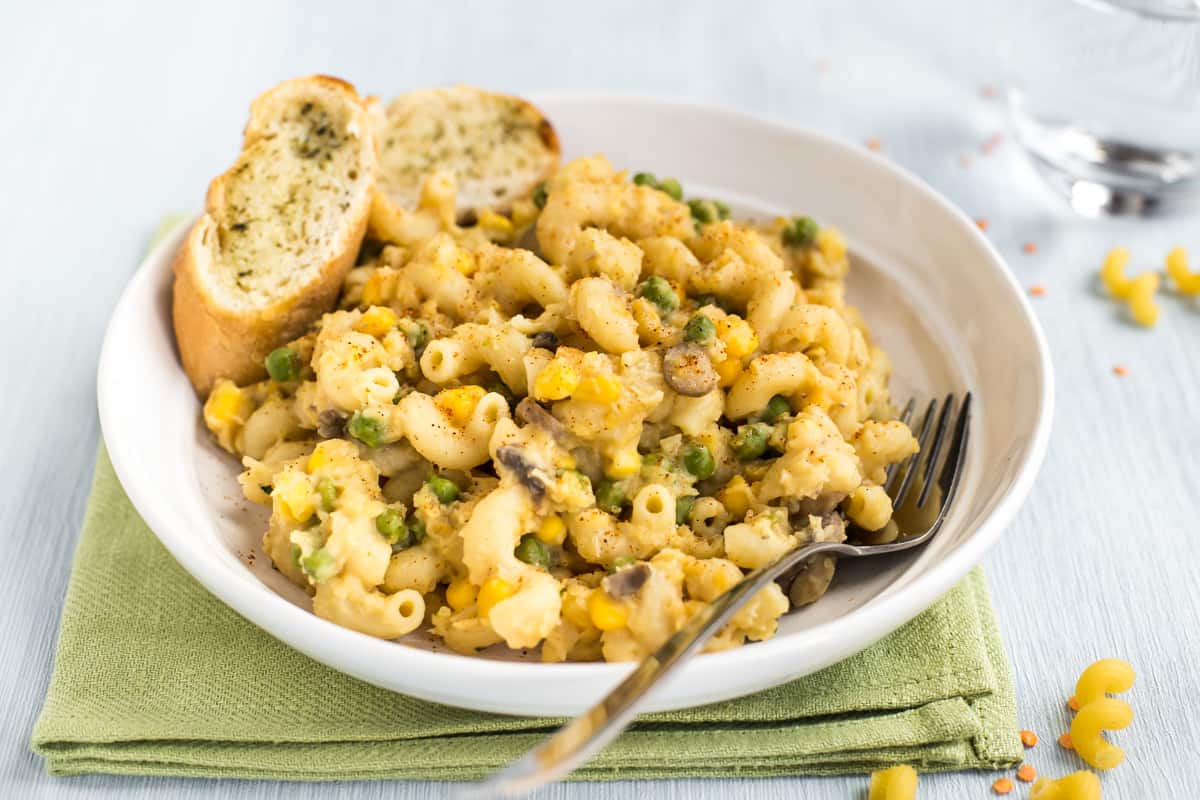Cheesy lentil pasta in a bowl served with garlic bread.