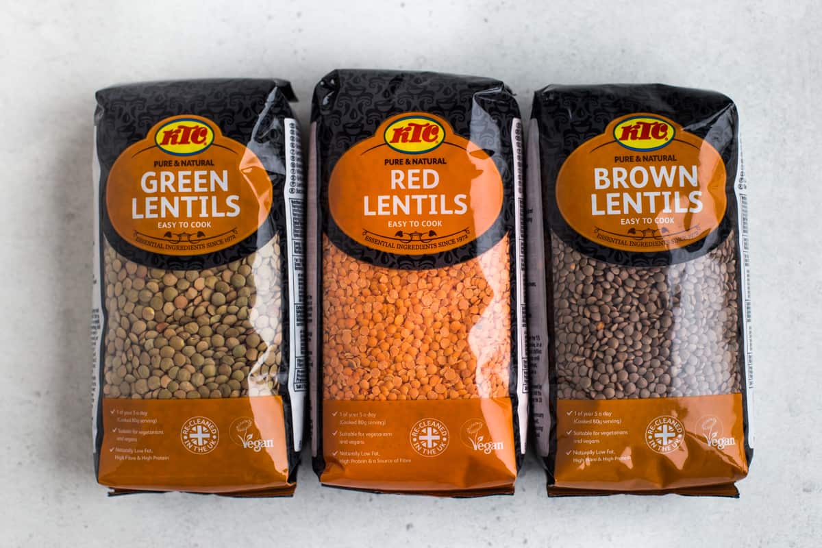 Packets of green, red and brown lentils next to each other.