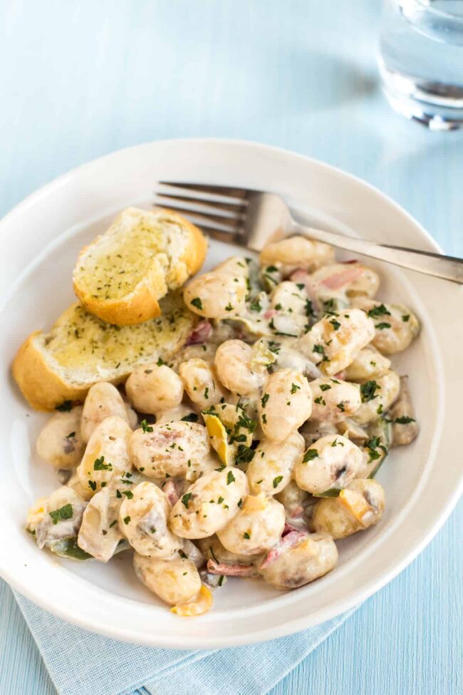 Gnocchi and vegetables in a creamy sauce with garlic bread.