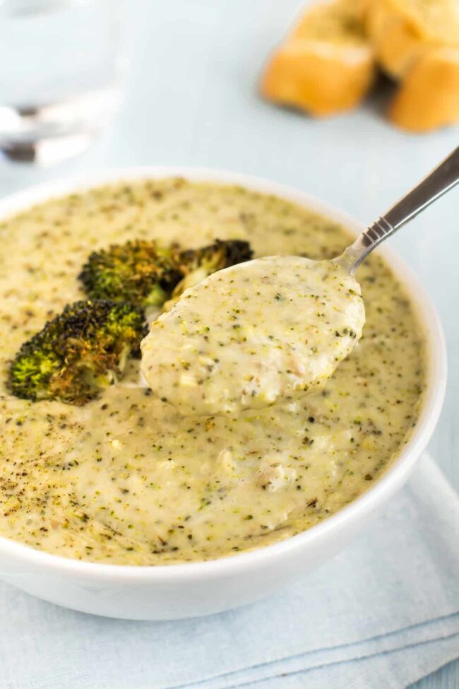 A spoonful of creamy broccoli soup being lifted up from a bowl.