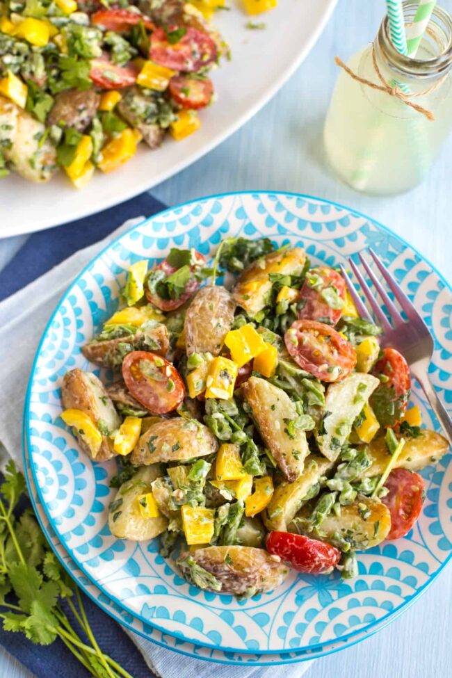 Creamy potato salad with vegetables on a plate.