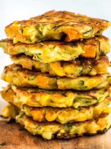 A stack of cheesy vegetable fritters on a board.