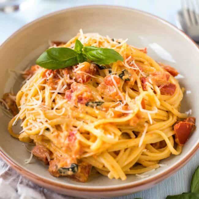 A bowlful of creamy tomato and mascarpone spaghetti topped with fresh basil.