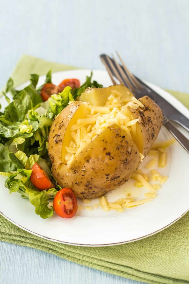 A cheesy baked potato served with salad.